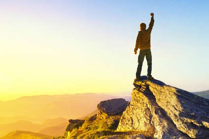 Man at the top of a mountain celebrating success